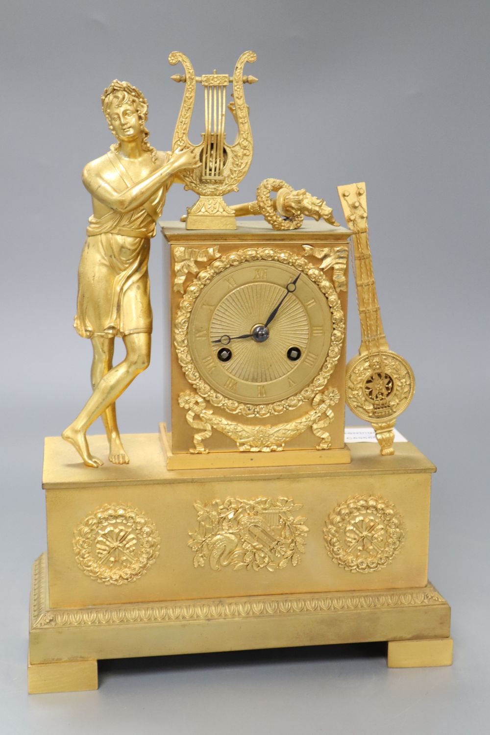 A French Empire design ormolu eight day mantel clock, the case surmounted with a Grecian figure playing a lyre, height 31cm